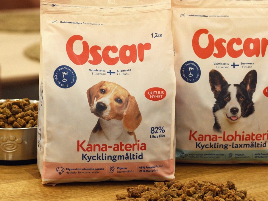 Bags of Oscar pet food on a table with biscuits scattered in front