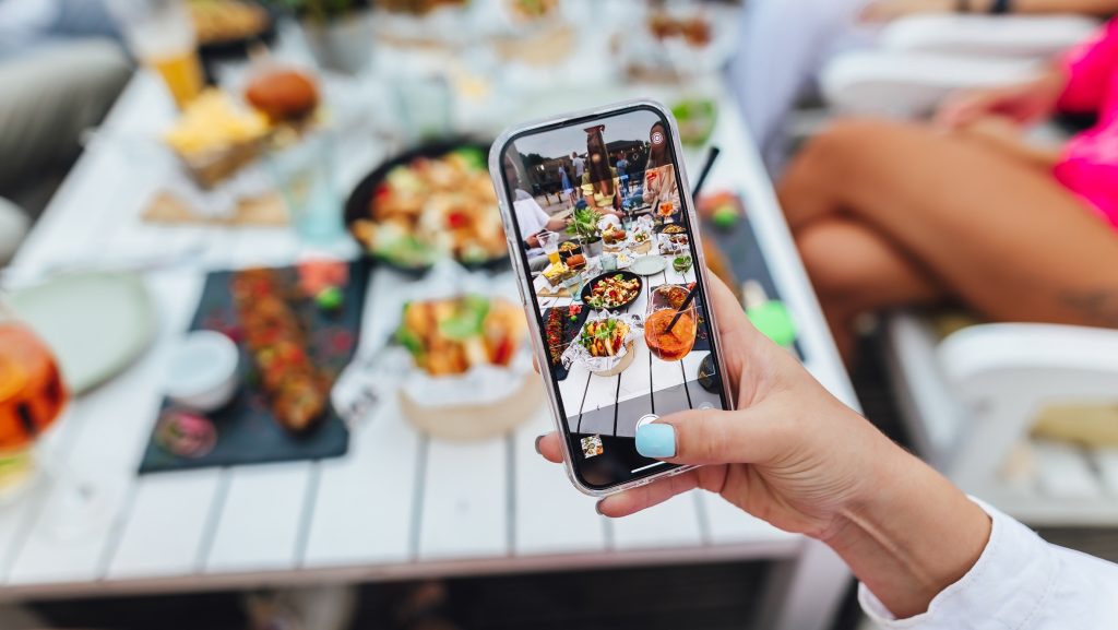 Person taking photo on smartphone of food at party